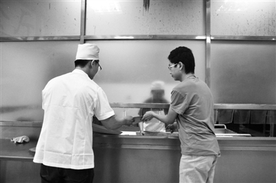 记者回收学生们吃完的餐盘。17日，中国农业大学东校区食堂，本报记者郭少峰（左）体验食堂后勤工作。