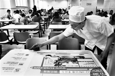 5月17日，中国农业大学东校区学生食堂内，本报记者郭少峰正在清理餐桌。