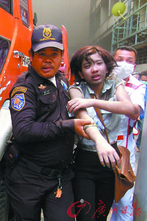 合艾市的五星级酒店爆炸后，警察将一位惊慌失措的女游客带离现场。